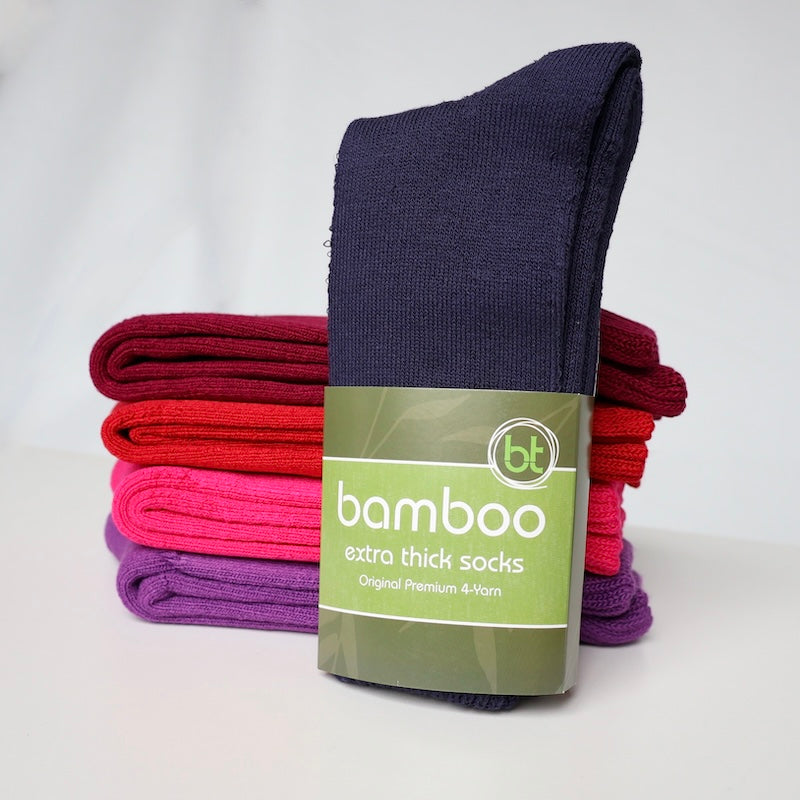 Navy extra thick bamboo socks in front of red, pink and purple socks in a stack