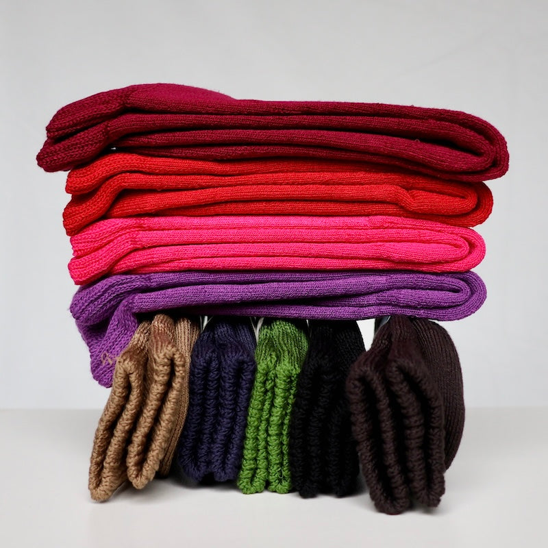 Multiple colours of extra thick bamboo socks stacked in a pile on a white background